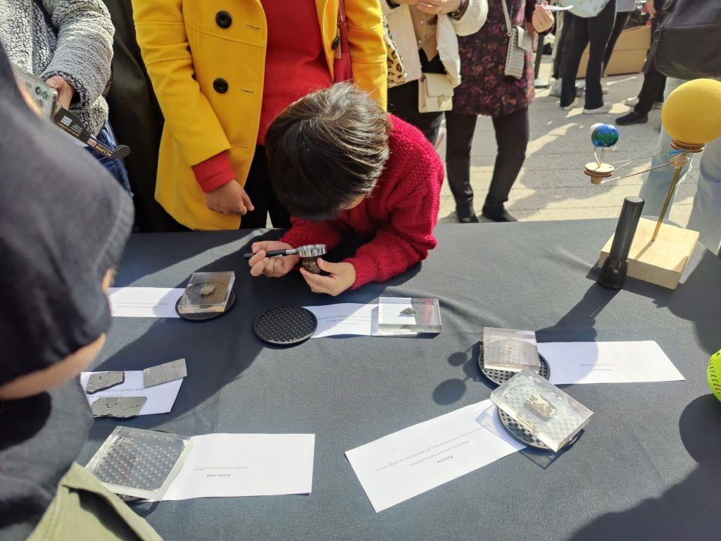 Child looking at meteorites through a magnifying glass