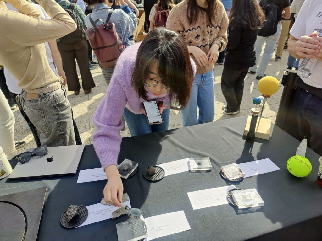 Person examining a lunar rock through a magnifying glass